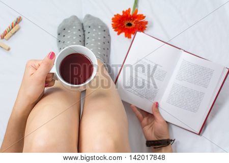 Woman Reading A Book And Having Cup Of Tea