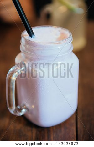 Refreshing blueberry milkshake in a glass. In a glass tube black