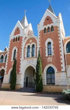 NEW NORCIA,WA,AUSTRALIA-JULY 15,2016: Red brick exterior of St. Gertrude's Ladies College with spanish gothic architecture and arched accents under a blue sky in the monastic town of New Norcia, Western Australia.