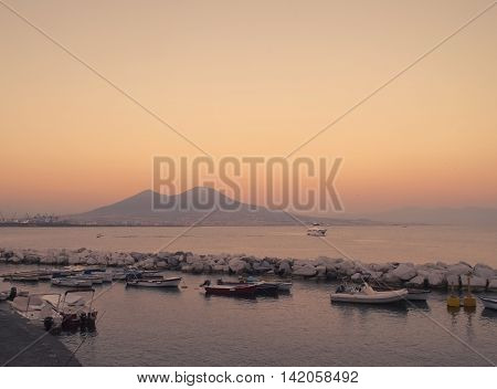 Harbour with boats in front of Mount Vesuvius in a summery sunset