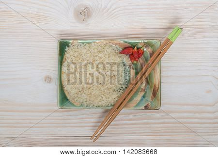 Rice with chopsticks in a bowl on the table in its raw form