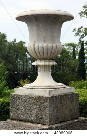 big beautiful white marble vase as small architectural forms in green park closeup