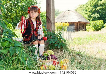 Ukrainian village. Girl in the national hutsul costume sitting with fruit