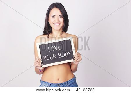Young woman holding chalkboard that reads Love Your Body. Self love concept.