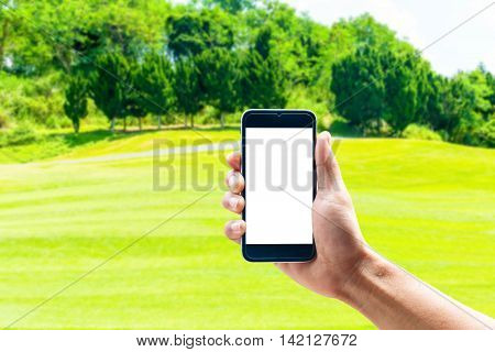 Hand using smartphone mobile in the vertical position, background blur of golf.