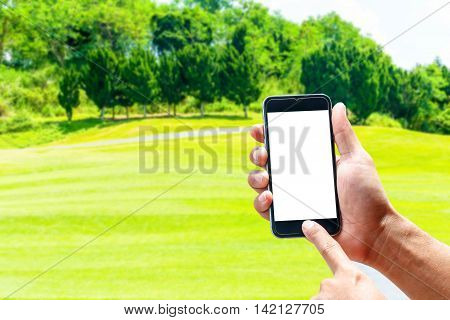 Hand using smartphone mobile in the vertical position, background blur of golf.
