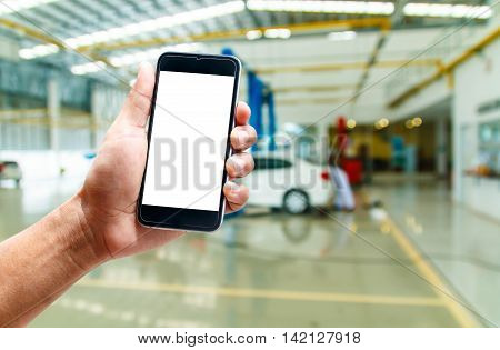 hand hold smartphone with car repair service center background blur