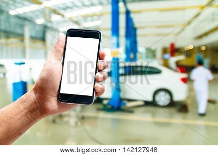 hand hold smartphone with car repair service center background blur