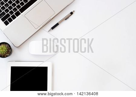 White office desk table with pen laptop mouse and empty screen tablet. Top view with copy space