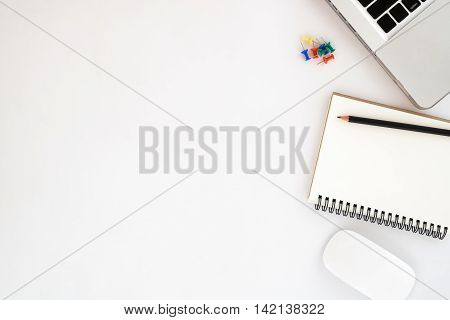 White office workspace with blank leather notebook pencil mouse and laptop. Top view with copy space