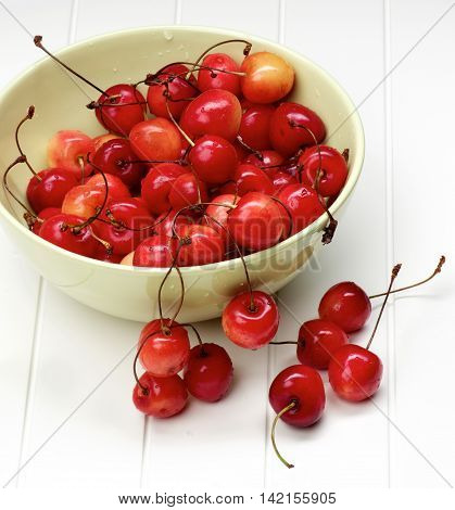 Heap of Fresh Ripe Sweet Maraschino Cherries in Green Bowl closeup on Plank White background