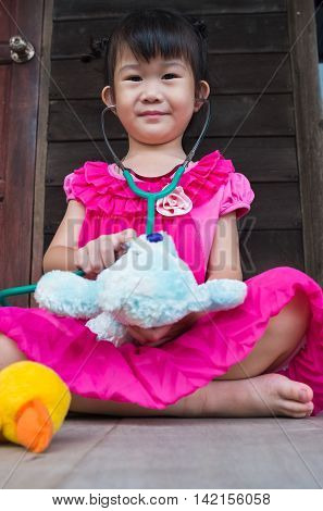 Adorable Asian Girl Playing Doctor Or Nurse With Plush Toy Bear At Home.