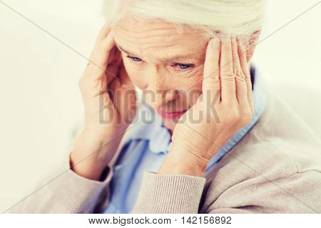 health care, pain, stress, age and people concept - face of senior woman suffering from headache