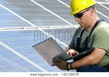 Green energy power plant and engineer with laptop