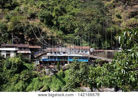 Syange, Nepal - October 24, 2014: A man crossing a suspension bridge over the Marsyangdi River