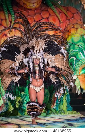 Parintis Brazil December 06 2015: One attractive smiling tallanted dancer woman in bikini and carnival feather costume bright blue colors and painted face in mask horizontal photo