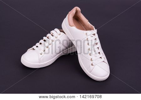 Women's white sport shoes on dark background