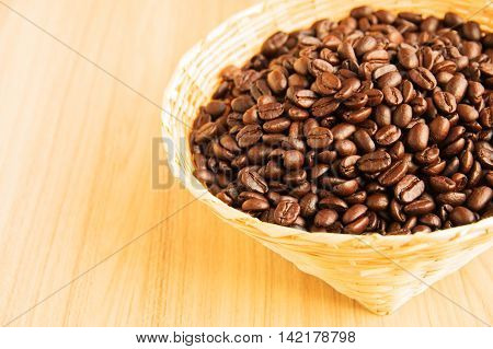 Coffee beans in bamboo panier on the wood background