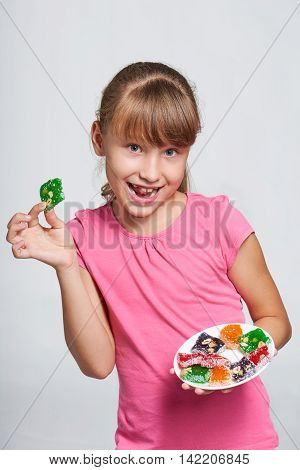 Happy playful little girl holding a plate with colorful jelly candies sweets Turkish delights
