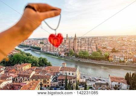 Holding decoration in the form of heart on the italian town Verona background. Verona is famous city of love in the north of Italy.