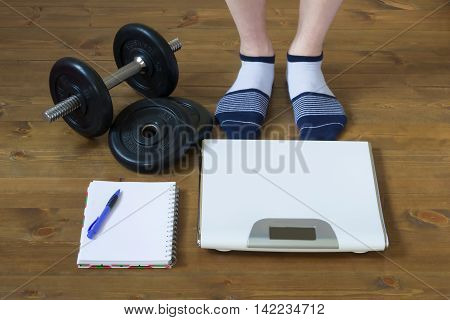 Legs in socks standing in front of the weights on the floor