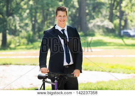Portrait Of Male Businessman Standing With His Bicycle At Park