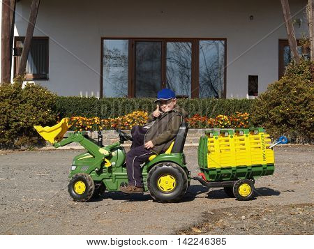 Little boy playing with toy-tractor on back yard