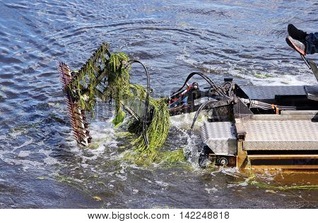 mini dredger is clearing lake algae summer day