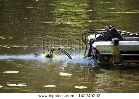 mini dredger is clearing lake algae summer day