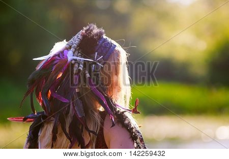 woman with war bonnet. the girl wears a homemade Indian headdress of feathers. roach, war bonnet. woman looked away. the concept of woman on the warpath