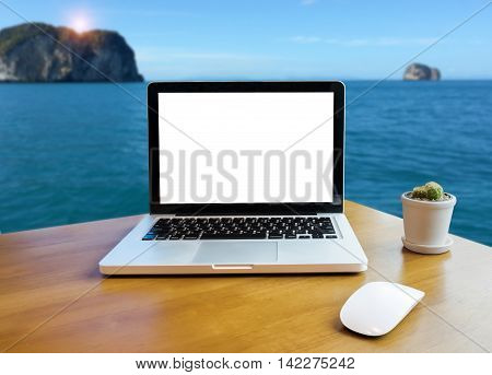 Front view of laptop on desk outdoor office and sea view blurred background. Laptop with blank screen and can be add your texts or others on Laptop. Laptop concept.