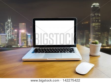 Front view of laptop on table in Office and night building blurred background