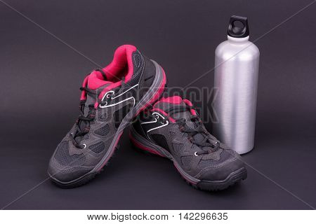 Women's hiking boots and water bottle on black background