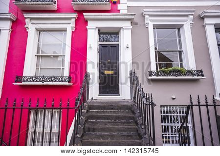 Red and grey painted typical colorful brick houses of Notting Hill district near Portobello road - London, UK