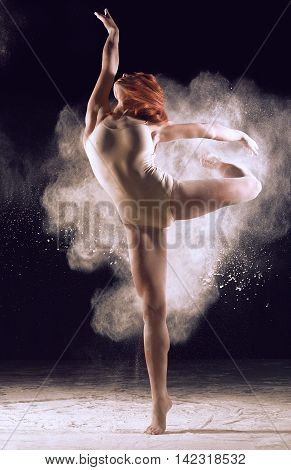 Dancer performing over black background with powder burst to show power and movement. Dancer performing over black background with powder.