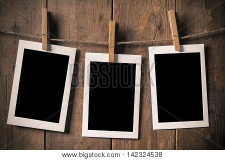 Blank Old Photo Frame Hanging on a Rope By Clothespin on Wood Background