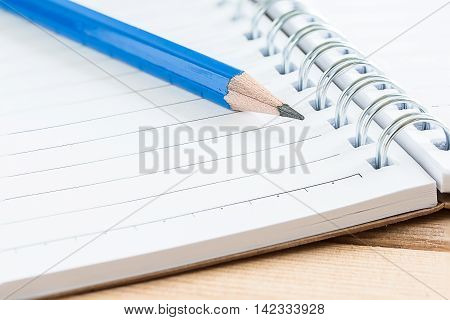 close-up notebook and pencil on wood table