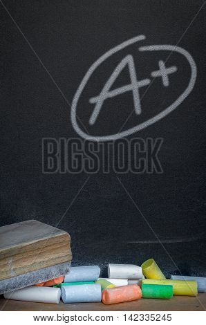 Colorful of chalk on wood table over grade a plus on black chalkboard background
