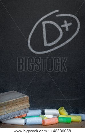 Colorful of chalk on wood table over grade d plus on black chalkboard background