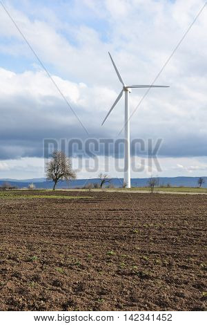 Spring landscape with wind turbine against a cloudy sky