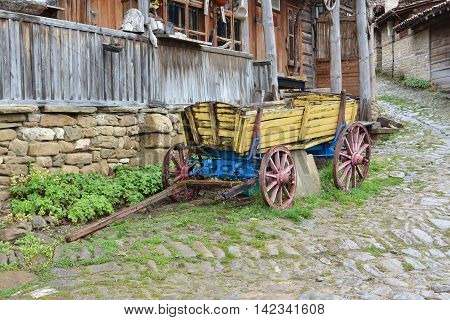 Yellow wooden cart in front of old house Jeravna village Bulgaria