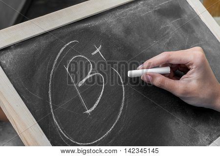 Young women write grade b plus on blackboard