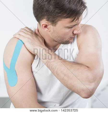 Picture of athletic man with arm pain during kinesiotherapy