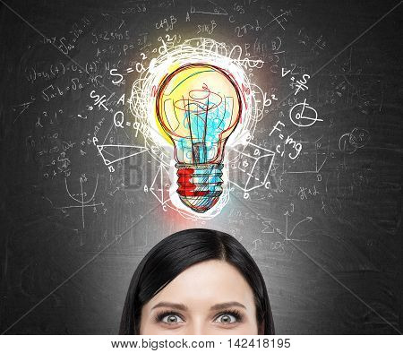 Close up Woman's head against blackboard with colorful light bulb sketch surrounded by formulas. Concept of new original idea