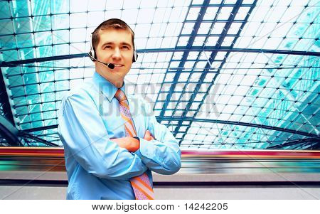 Homme d'affaires de bonheur en headphoness sur le fond d'architecture d'entreprise