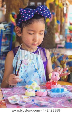 Cute asian girl painting plaster statue filterd color.