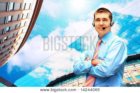 Homme d'affaires de bonheur en headphoness sur le fond d'architecture d'entreprise