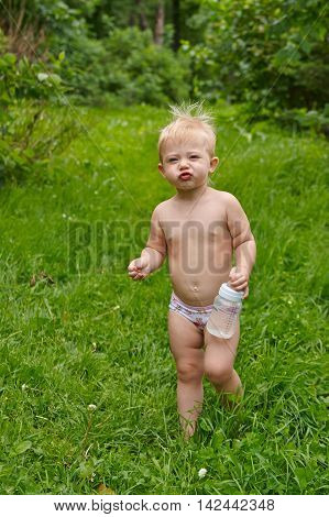Little kid in shorts walking barefoot on the grass