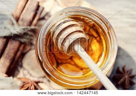 Golden honey with honeystick. cinnamon and anise stars on wooden table