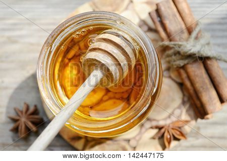 Golden honey with honeystick. cinnamon and anise stars on wooden table